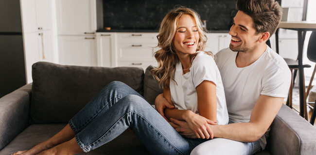casal em relação saudável, sentados no sofá a rir